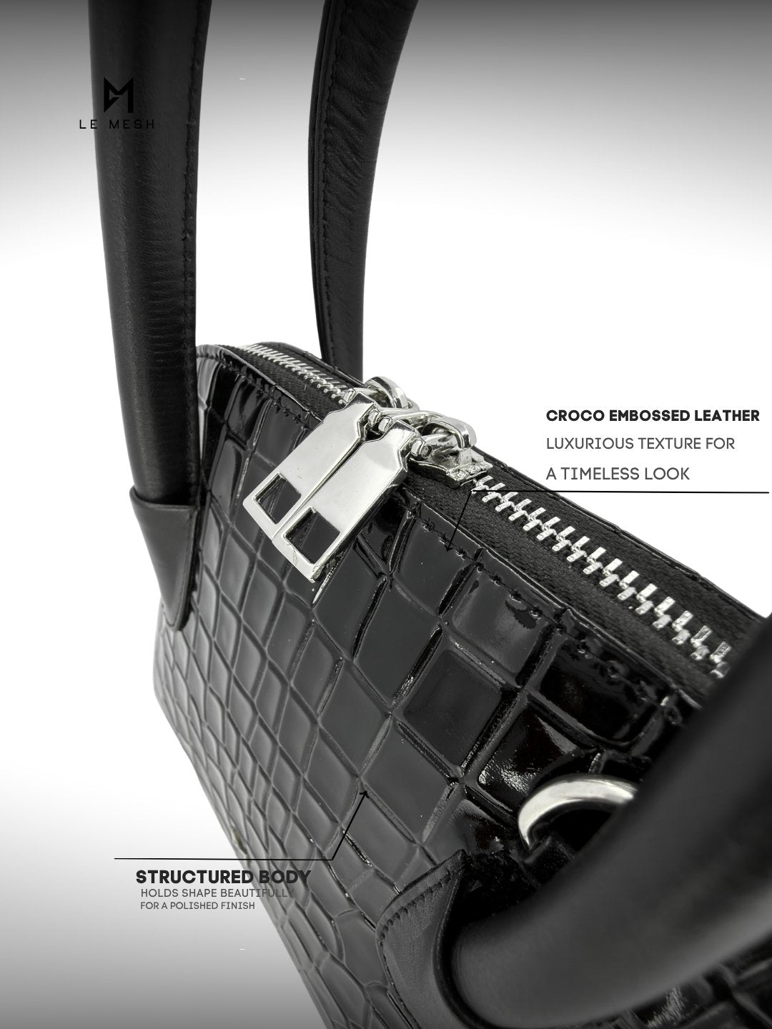 Black crocodile embossed leather handbag with silver hardware on a gray background