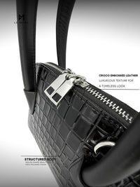 Black crocodile embossed leather handbag with silver hardware on a gray background