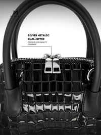 Black handbag with silver metallic dual zipper on a light gray background