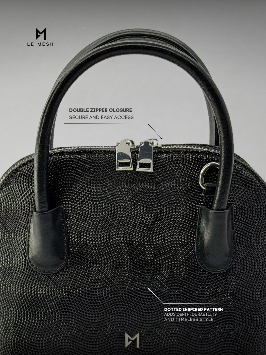 Black handbag with double zipper closure on a gray background, featuring Le Mesh branding.