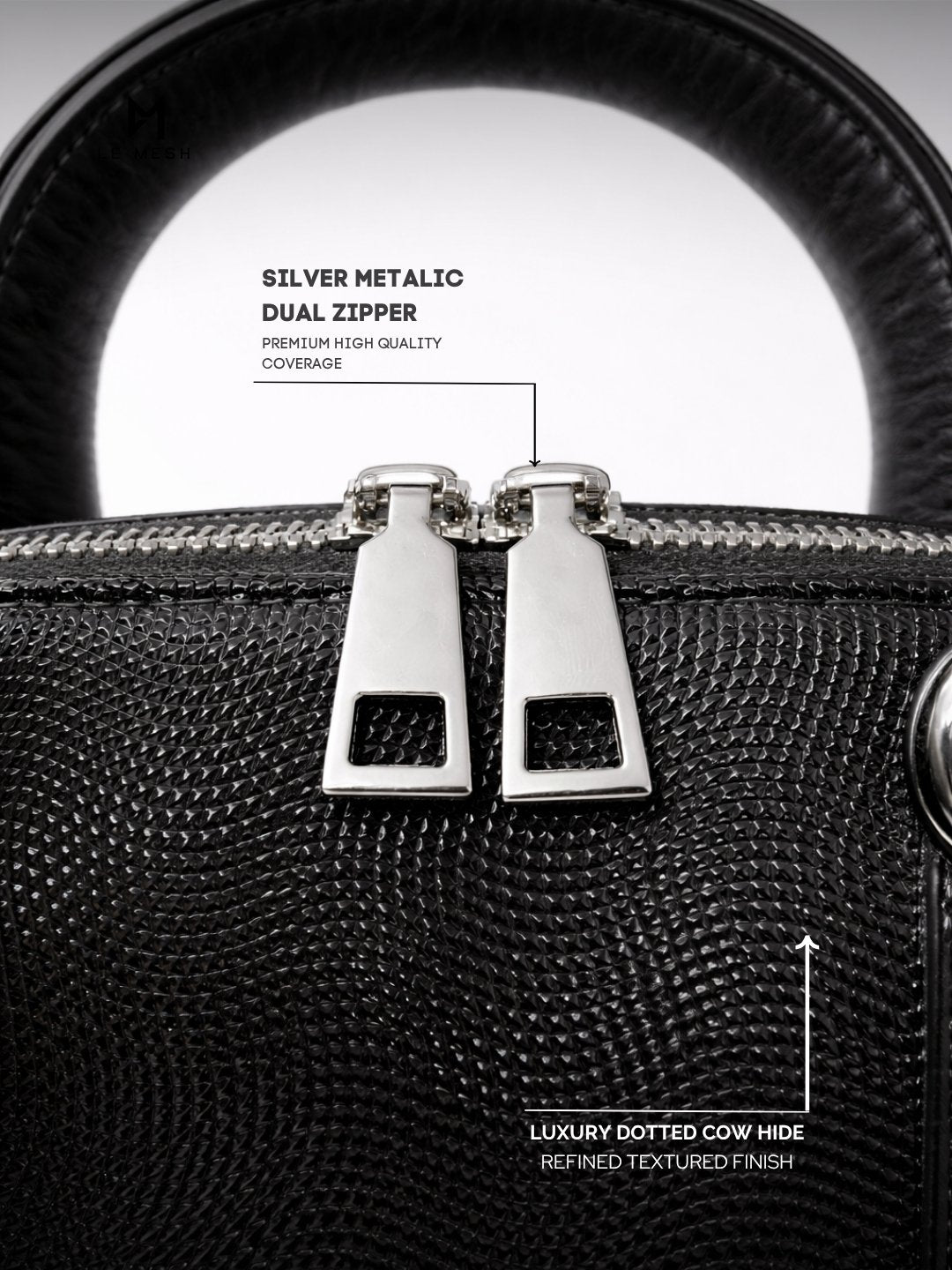 Black textured handbag with silver dual zipper, highlighting material and design features.