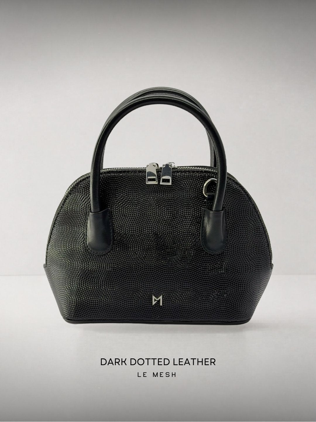 Black dotted leather handbag on a light gray background