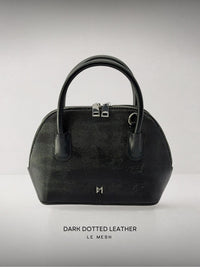 Black dotted leather handbag on a light gray background