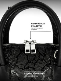 Black handbag with silver metallic dual zipper and premium stitching details on a white background.